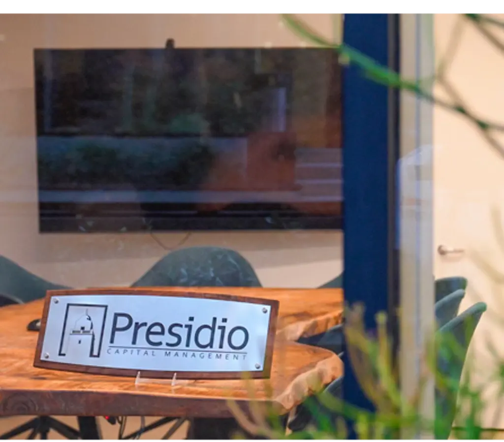 Conference room with a "Presidio Capital Management" sign on a table.