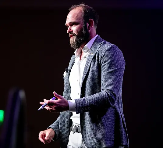 Man in business attire speaking on stage at a conference.