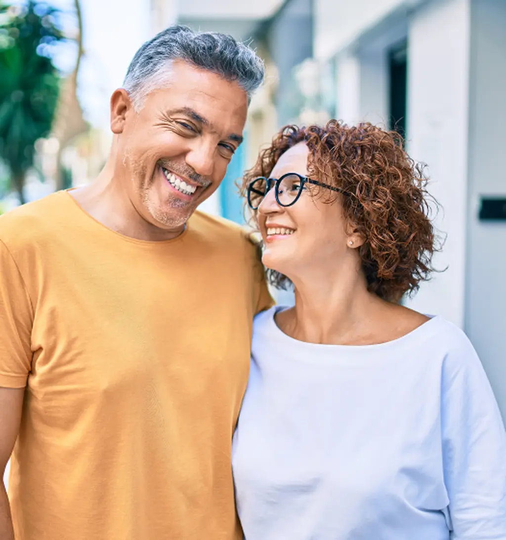 Smiling senior couple standing outdoors and looking at each other.