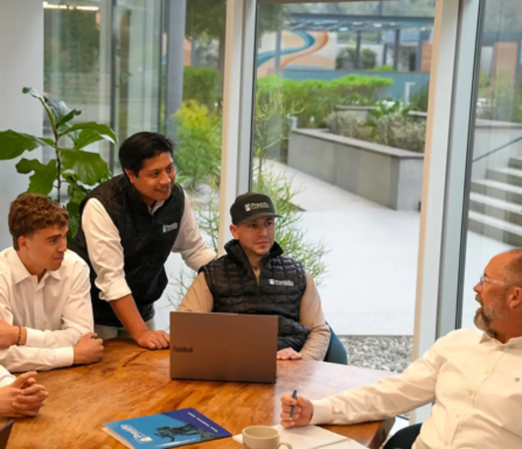 Four men discussing around a conference table with a laptop.
