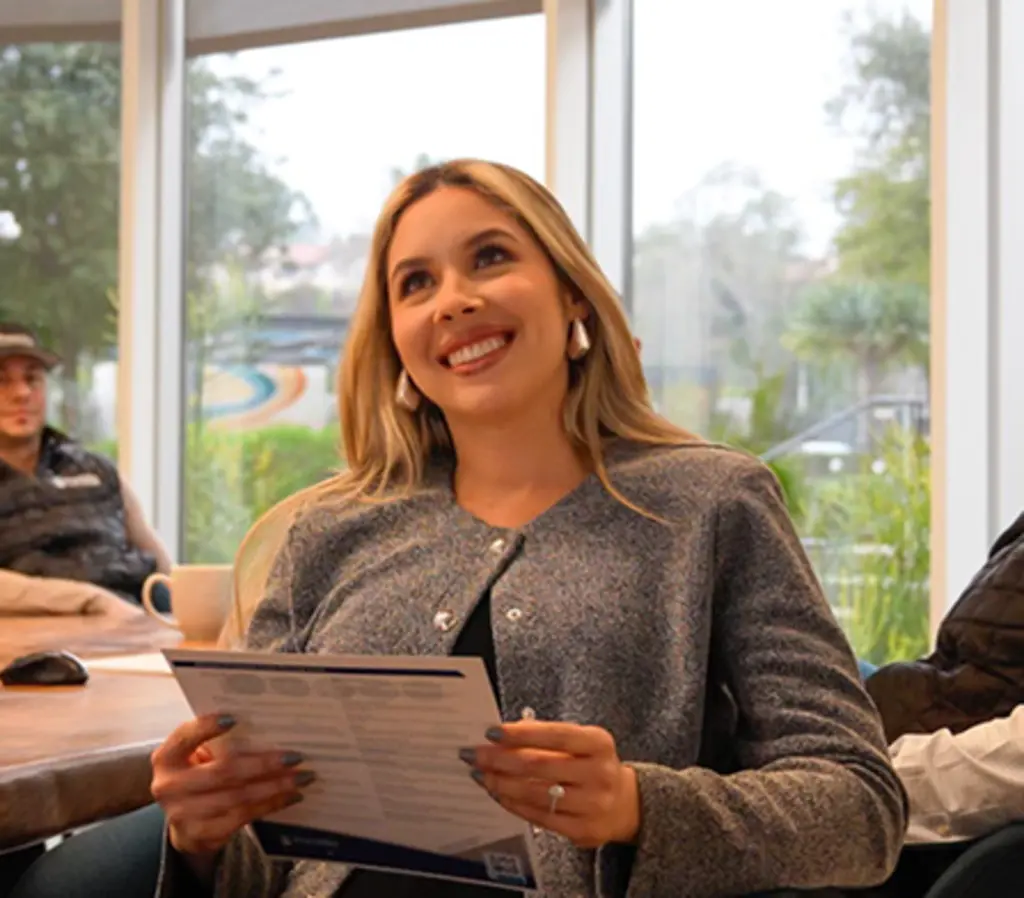 Woman smiling while holding a document in a meeting room.